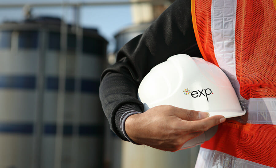 A man is holding a hard hat with the word exp on it.