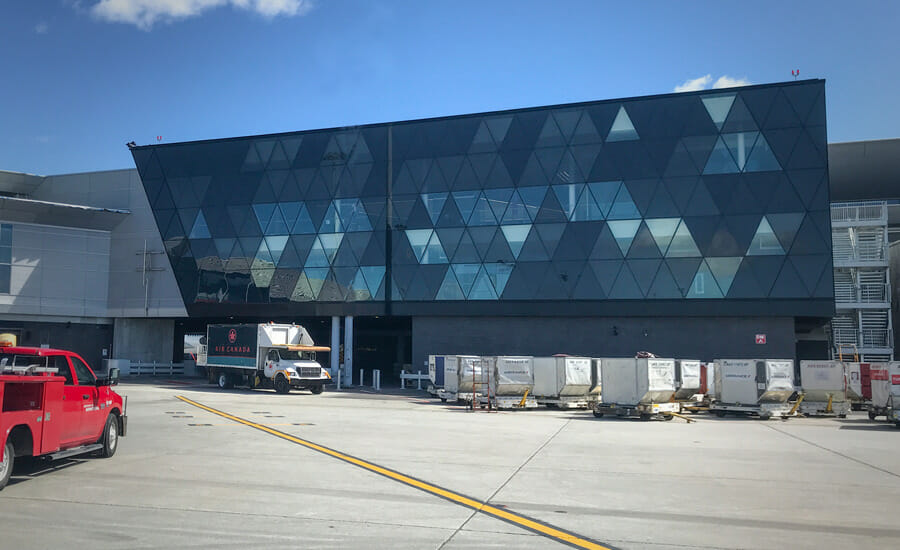 A red truck is parked in front of an airport building.