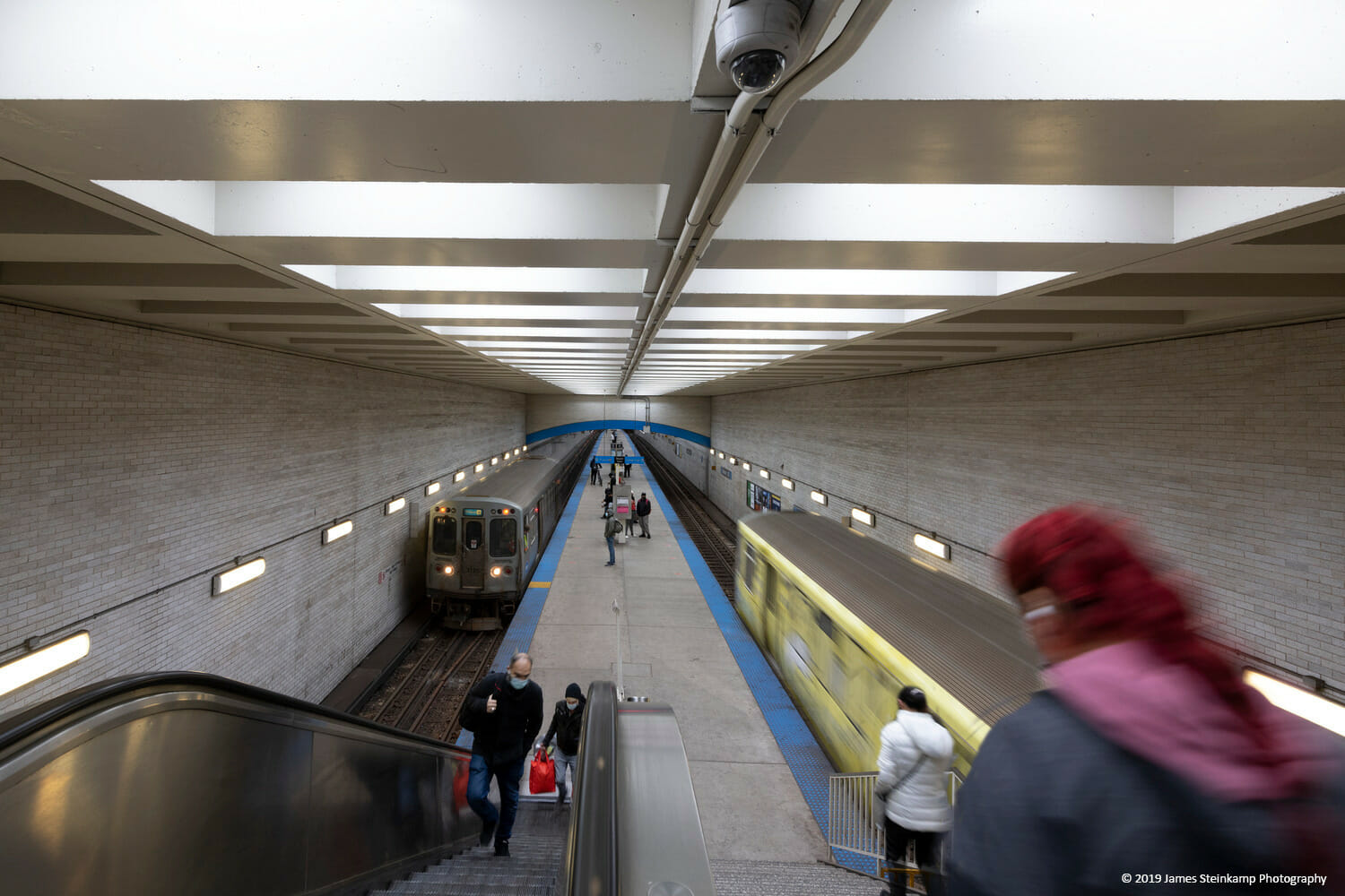 Une femme descend un escalier roulant dans une station de métro.