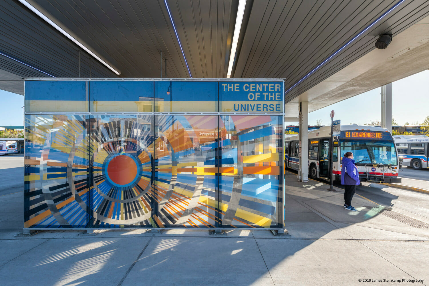 A bus stops in front of a bus shelter.