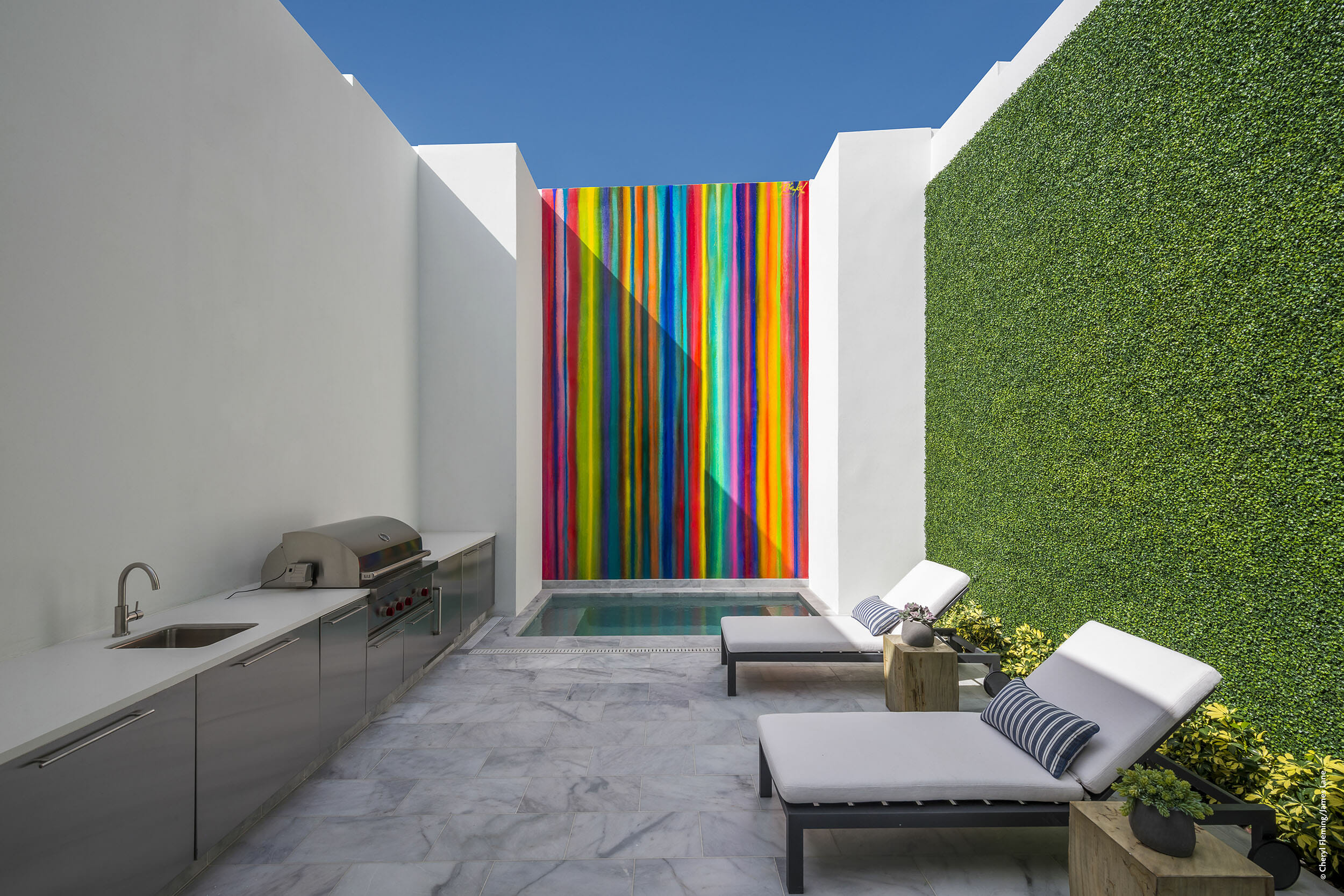 A backyard with a colorful wall and chairs.