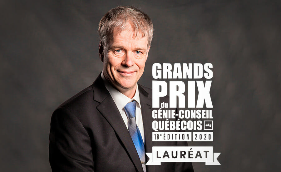 Un homme en costume-cravate se tient devant une pancarte indiquant grand prix.