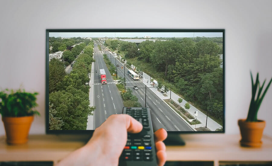 Une personne tient une télécommande tout en regardant la télévision.