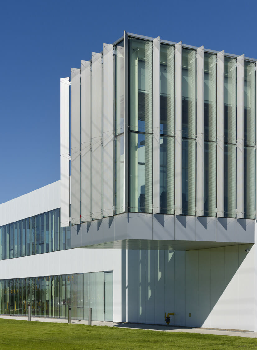 A modern building with glass walls and a grassy field.