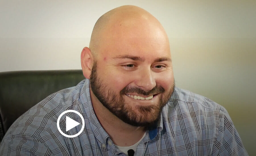 A man with a bald head is smiling in an office.