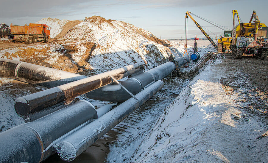 A group of pipes are being installed in a snowy area.
