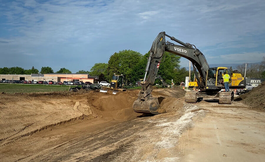 An excavator is working on a dirt road.