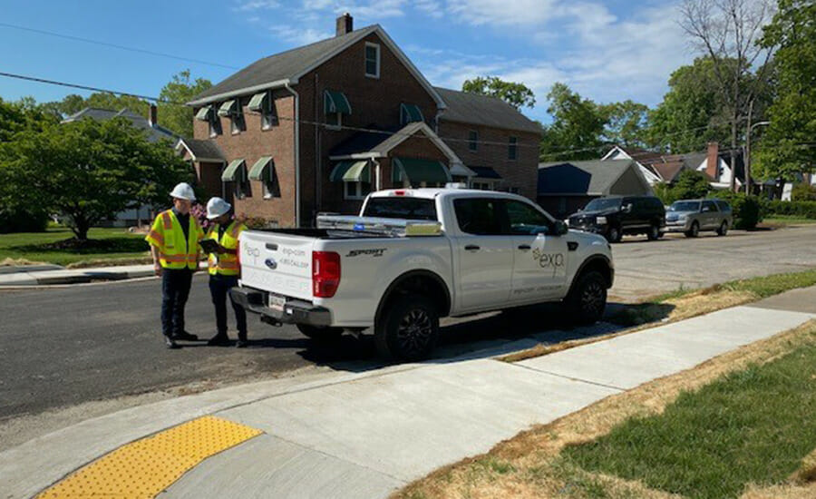 Two men standing next to a truck in front of a house.