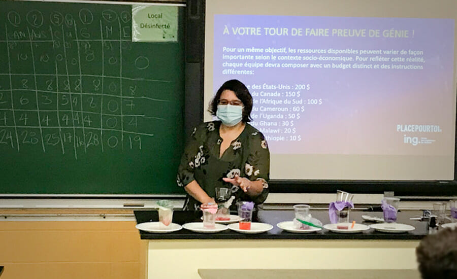 Une femme portant un masque devant un tableau noir.