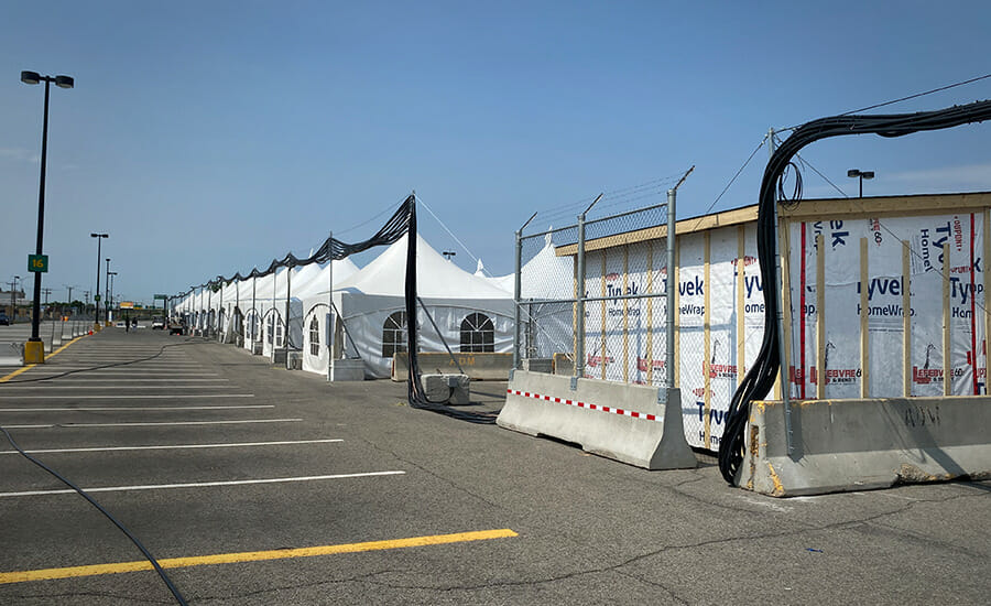 Une rangée de tentes blanches sur un parking.