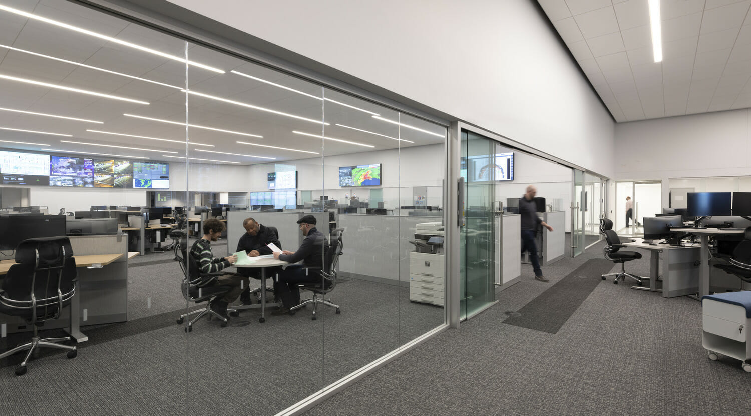 Un bureau en verre avec des personnes travaillant aux bureaux.