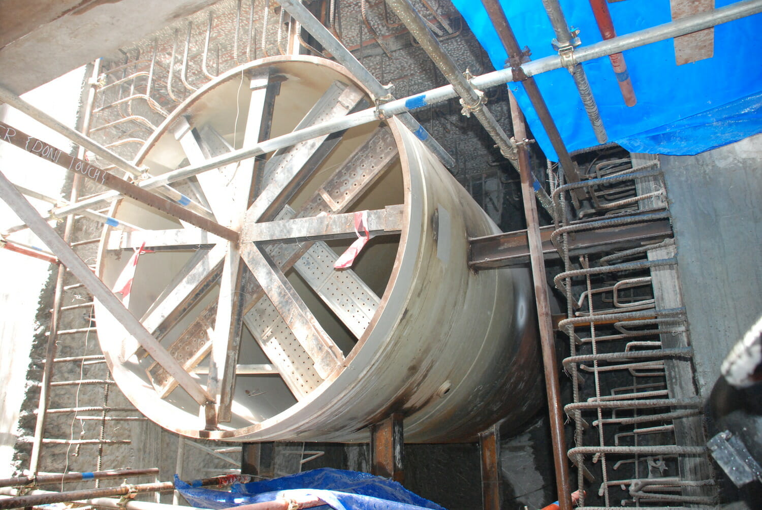 Une grande roue métallique est en cours d'installation dans un bâtiment.