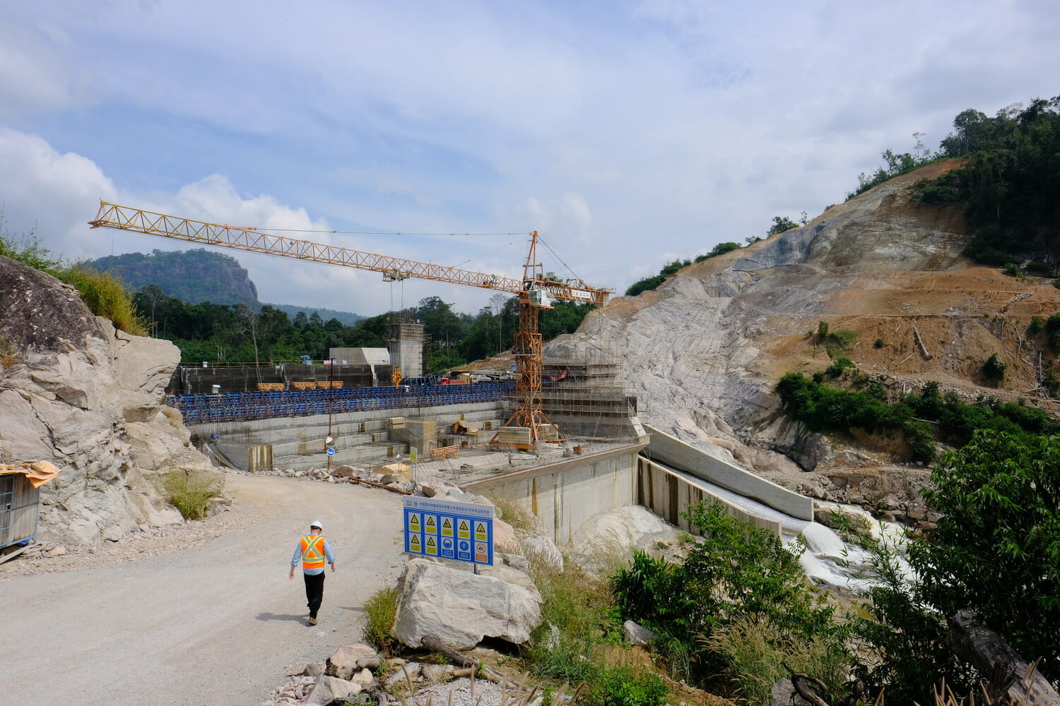 A man walking down a road next to a construction site.