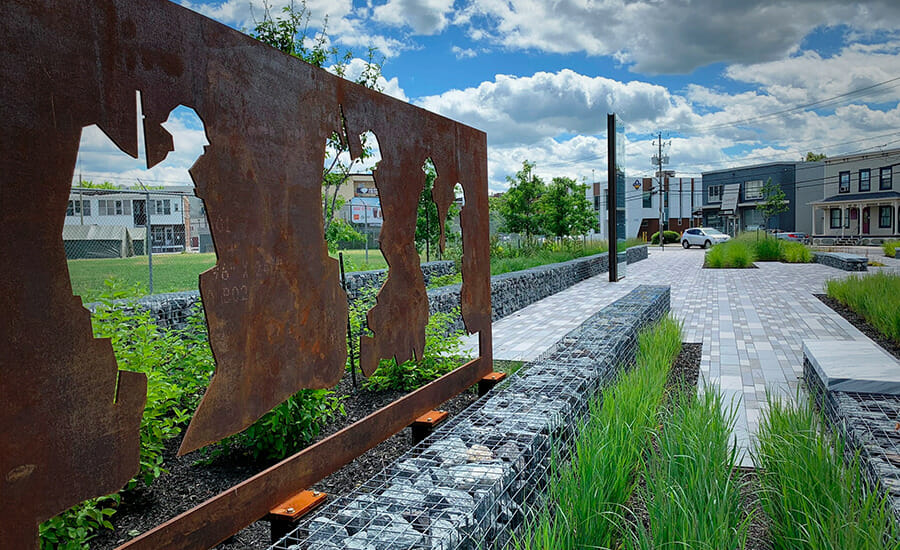 Une sculpture en métal rouillé trône au milieu d’un trottoir.