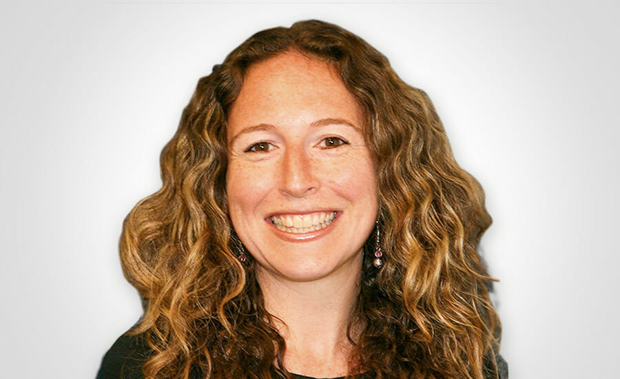 A woman with curly hair smiling for the camera.