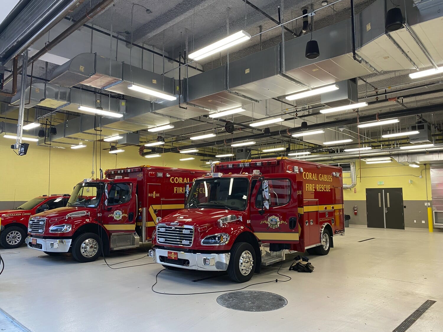 Two red fire trucks parked in a large room.