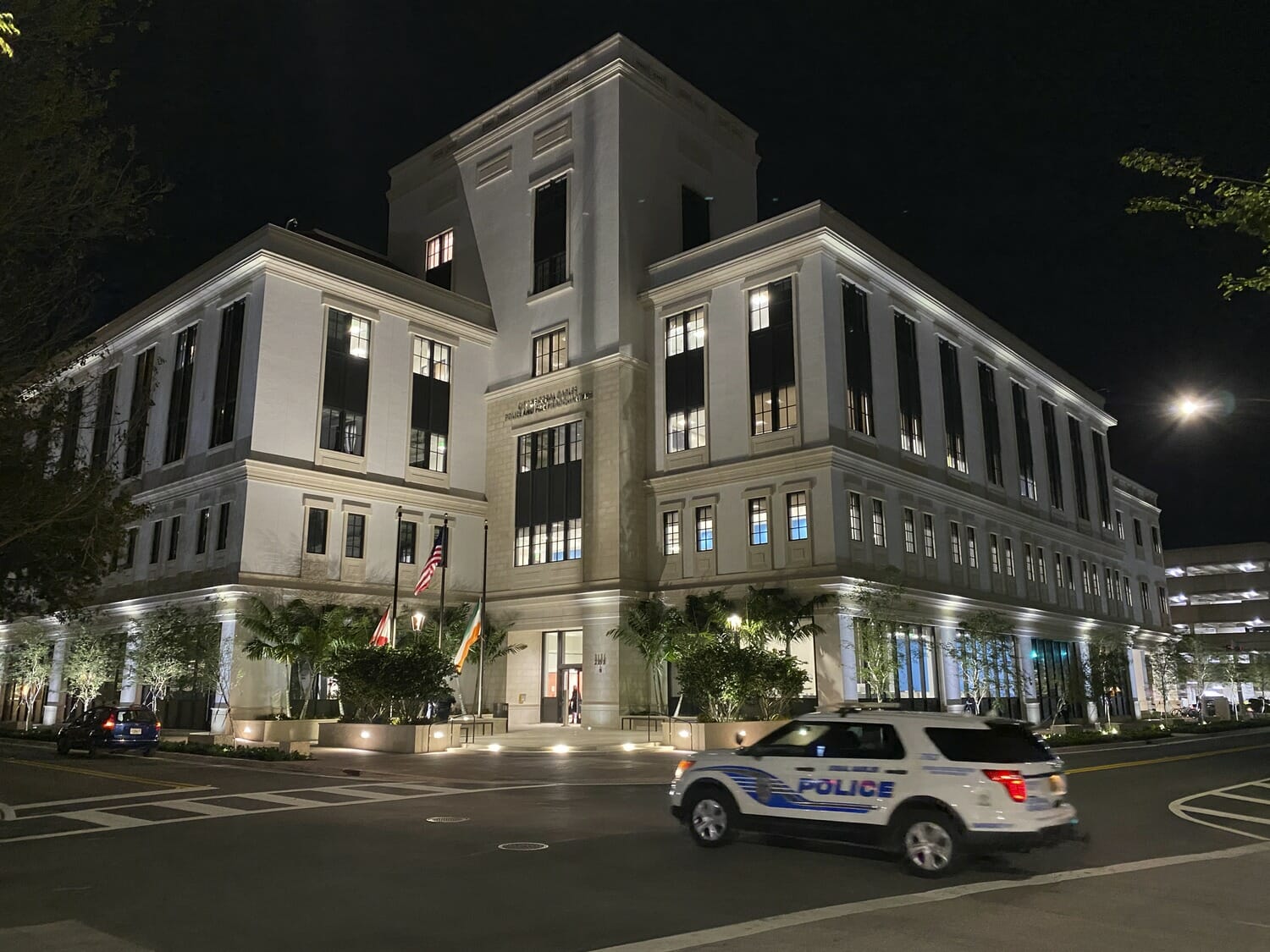A police car is parked in front of a building at night.