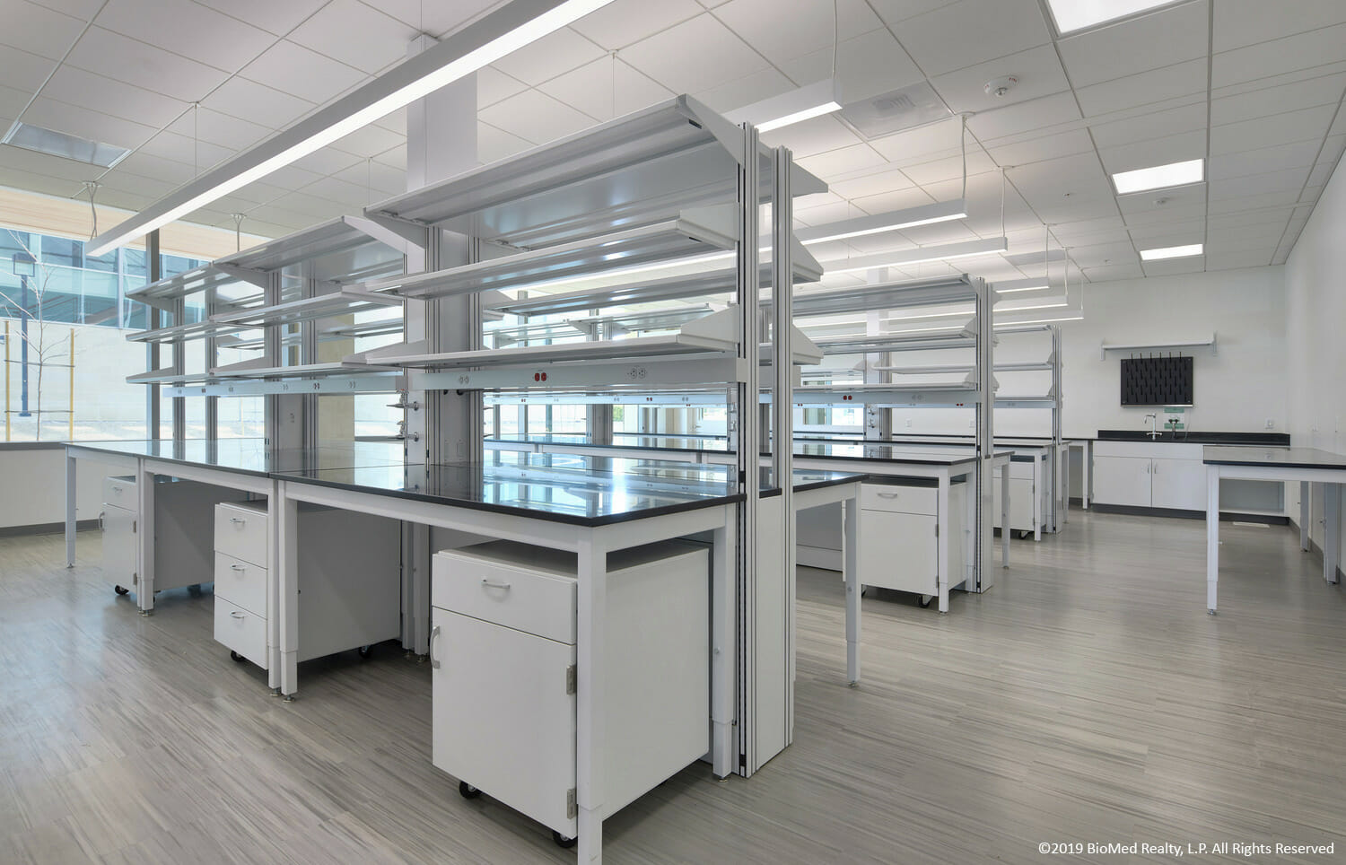 A large laboratory with white counter tops and shelves.