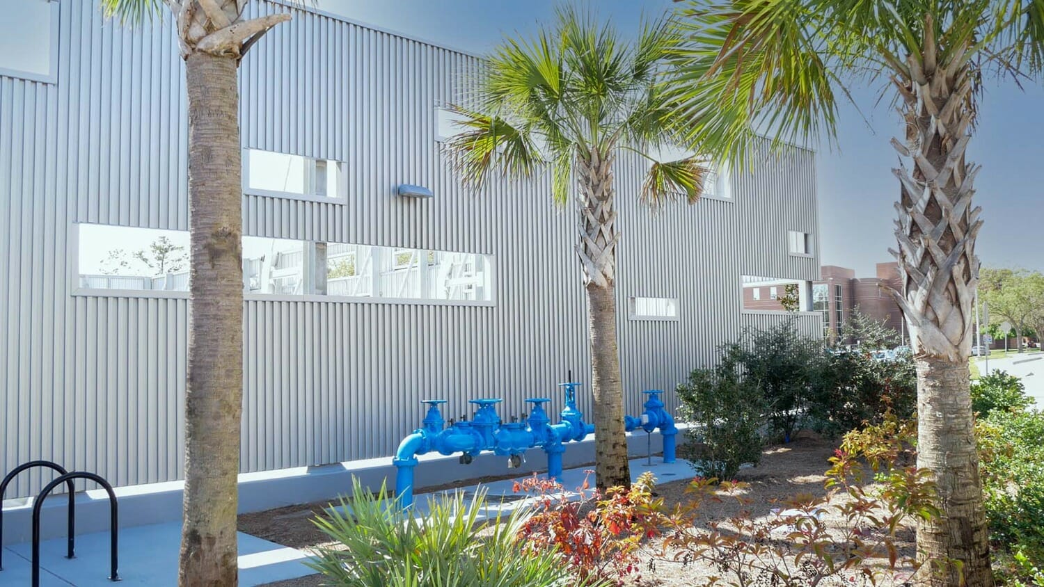A building with a blue fence and palm trees.