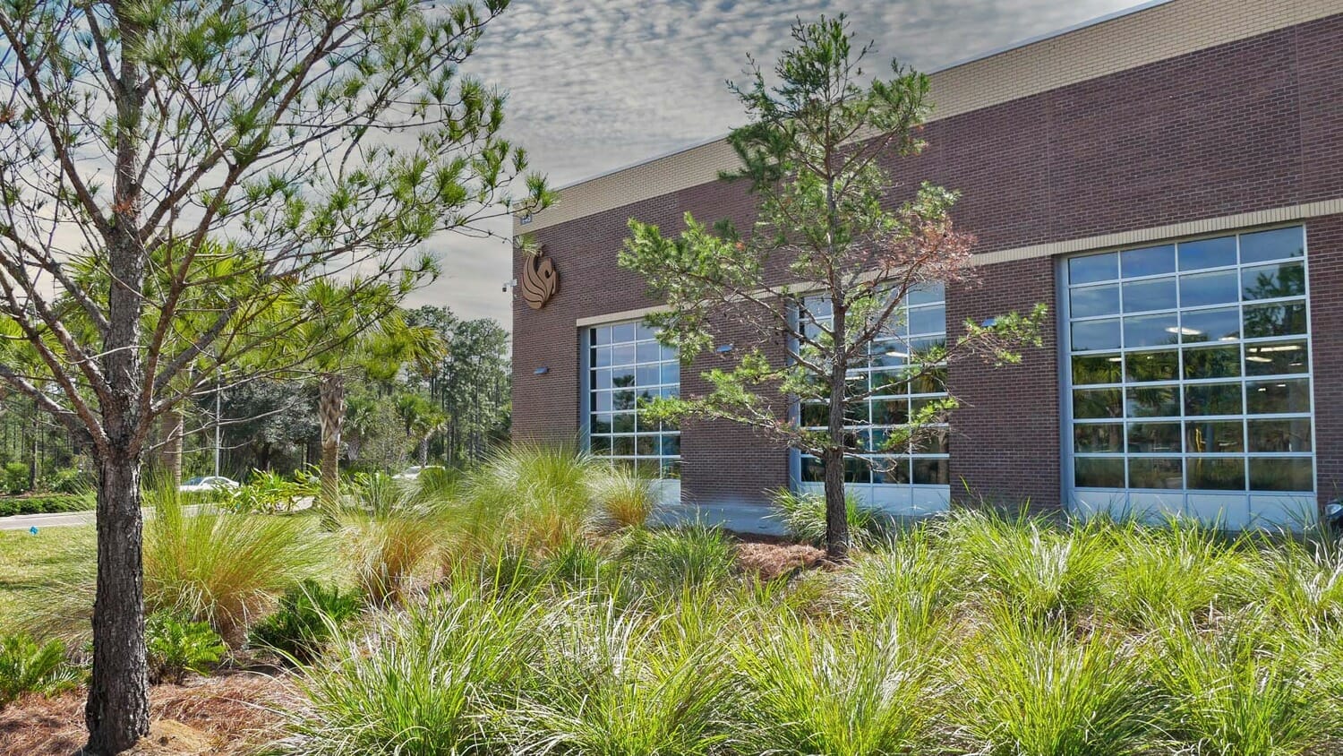 Un bâtiment avec de l'herbe et des arbres devant.