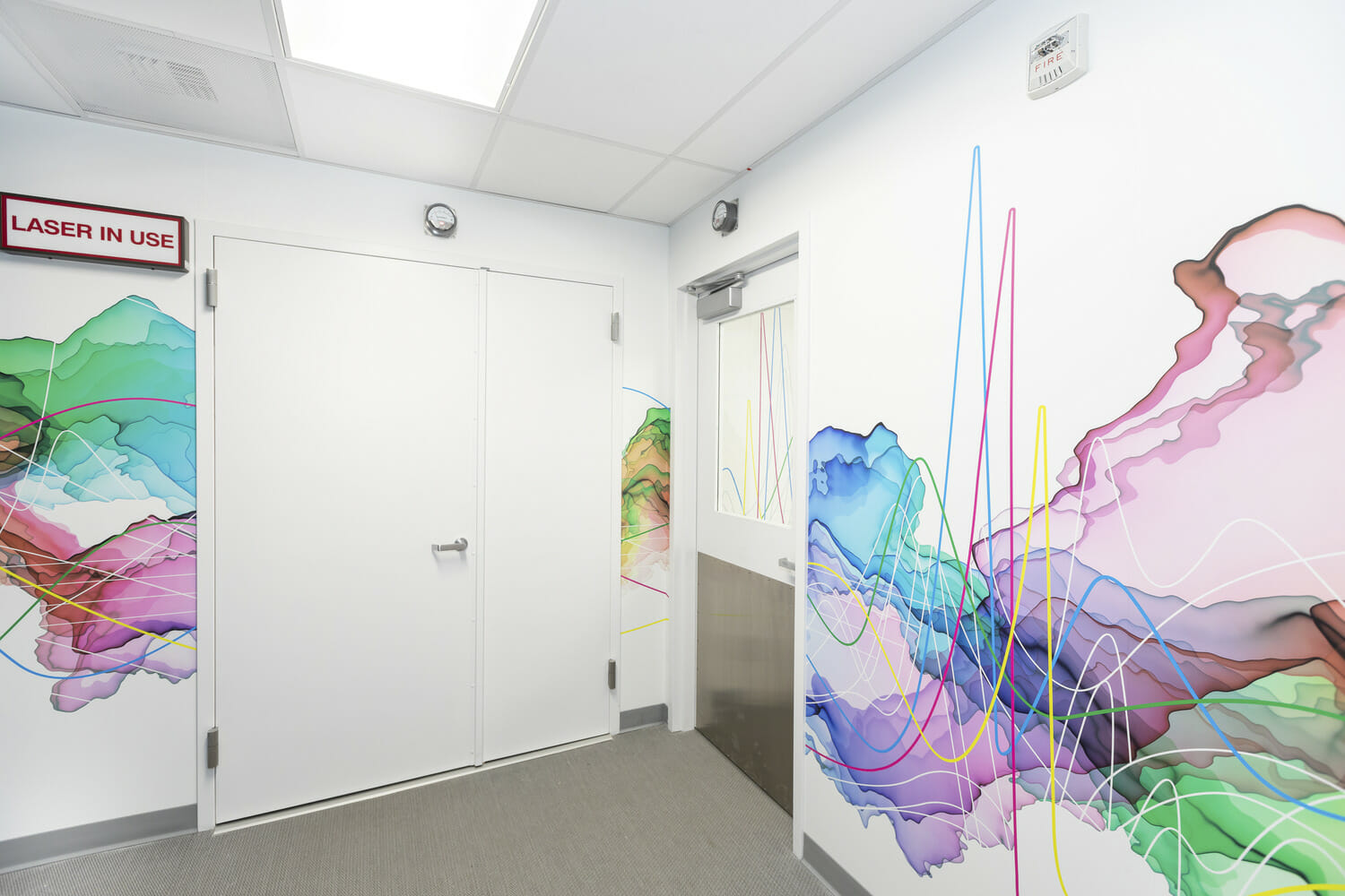 Un couloir avec une fresque colorée au mur.