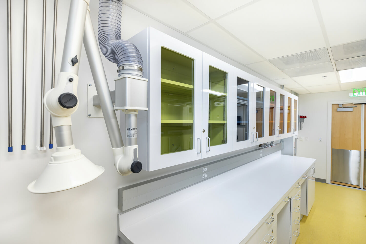 Un laboratoire médical avec un comptoir blanc et des armoires jaunes.