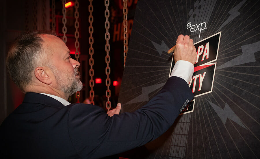 A man in a suit writing on a blackboard.