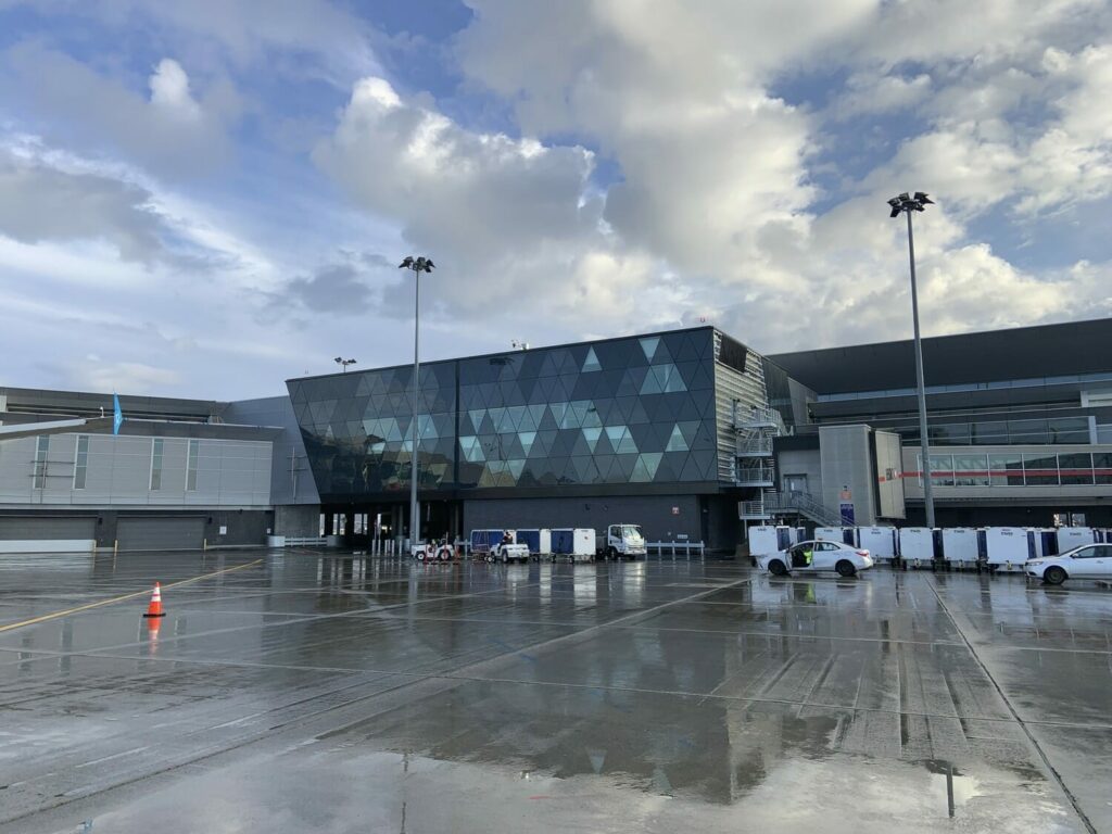 A large airport with parked cars and a cloudy sky.