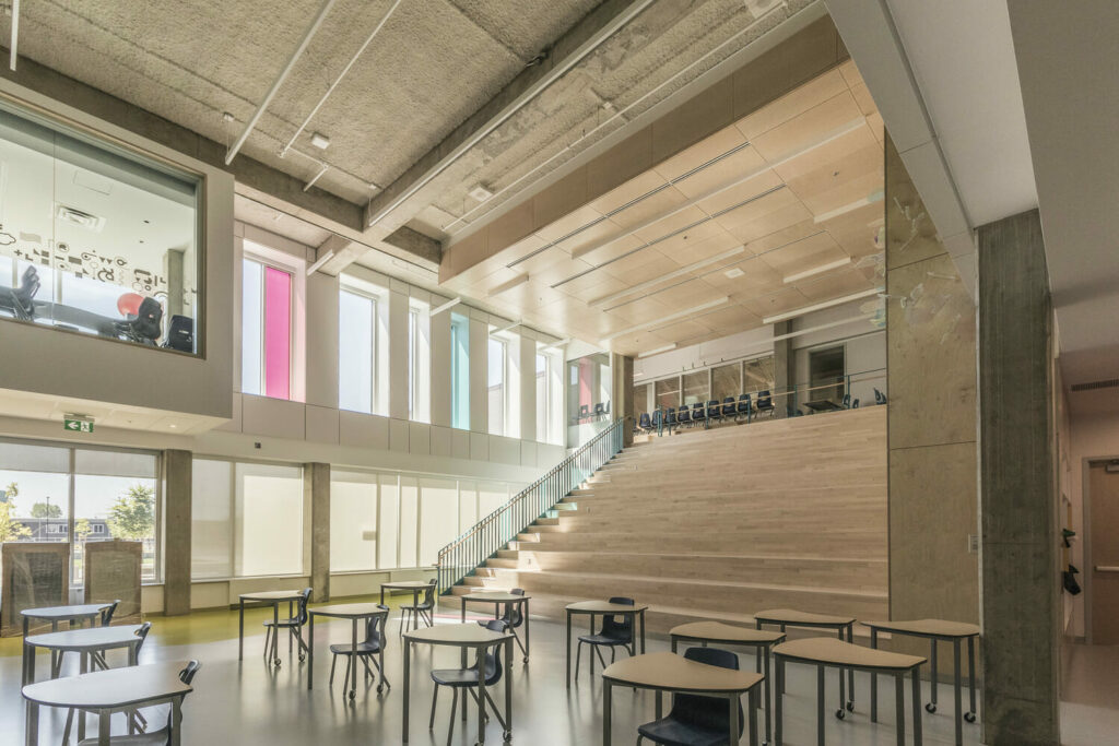 L'intérieur d'un bâtiment scolaire avec des escaliers et des tables.