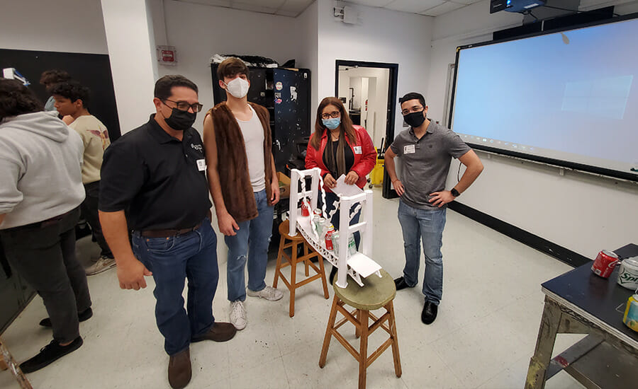 A group of people standing around a table with a model.