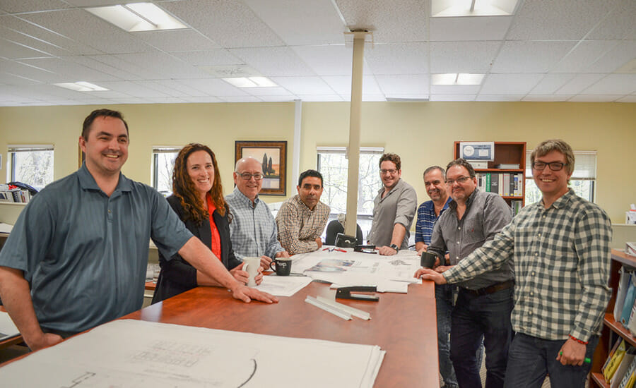 A group of people standing around a table with blueprints.