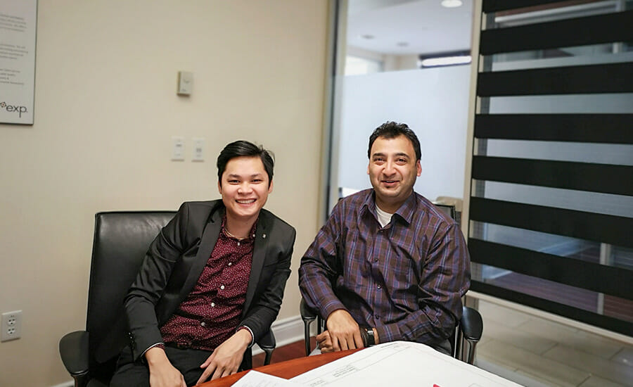 Two people sitting at a desk with papers in front of them.