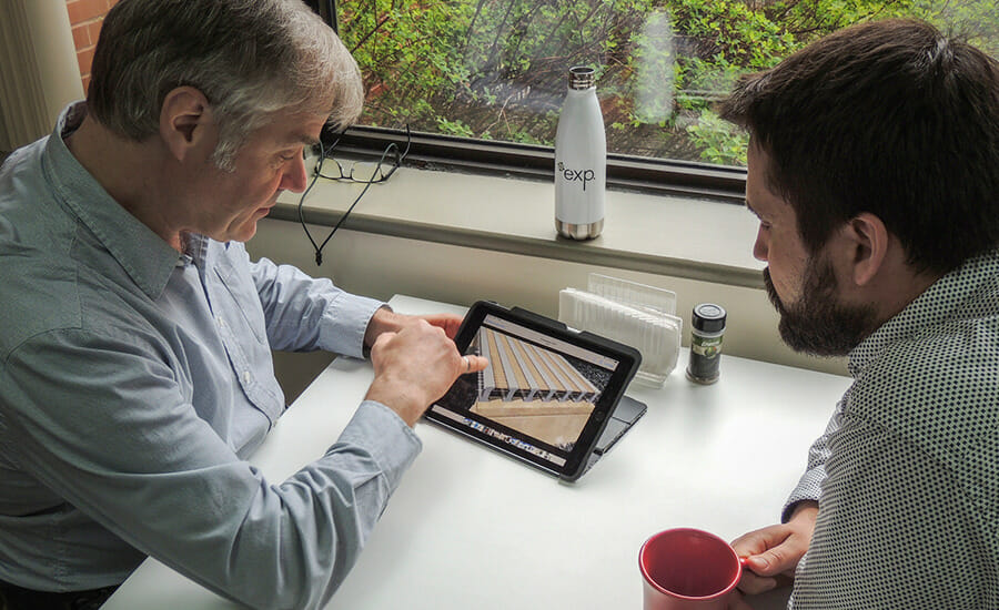 Two men sitting at a table looking at an ipad.