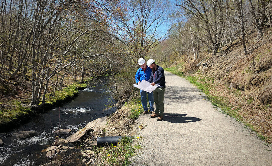 Deux personnes debout sur un chemin près d’une rivière.