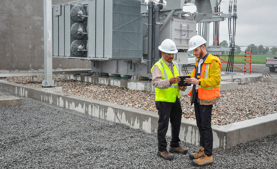Two construction workers looking at a tablet.