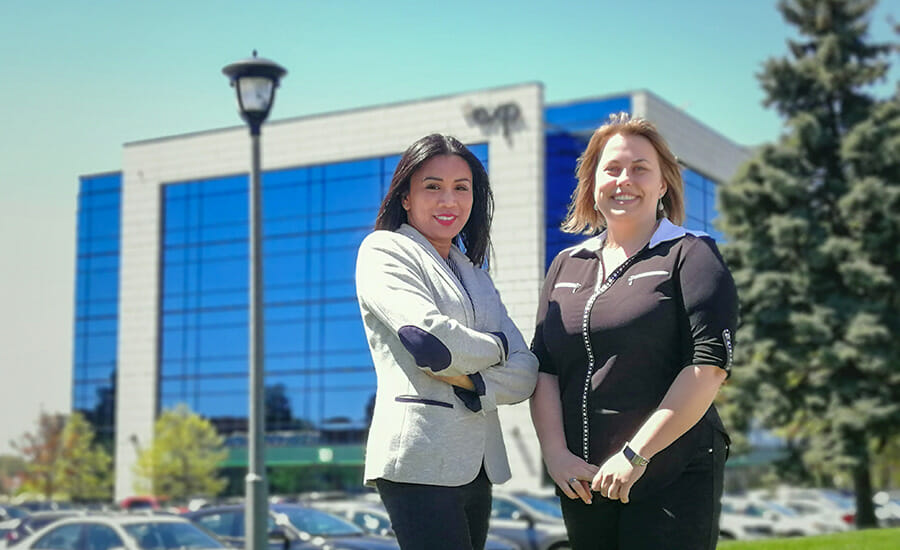 Deux femmes debout devant un immeuble de bureaux.