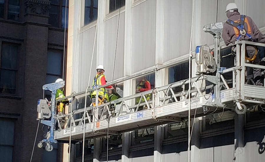 A group of workers on a ladder on the side of a building.