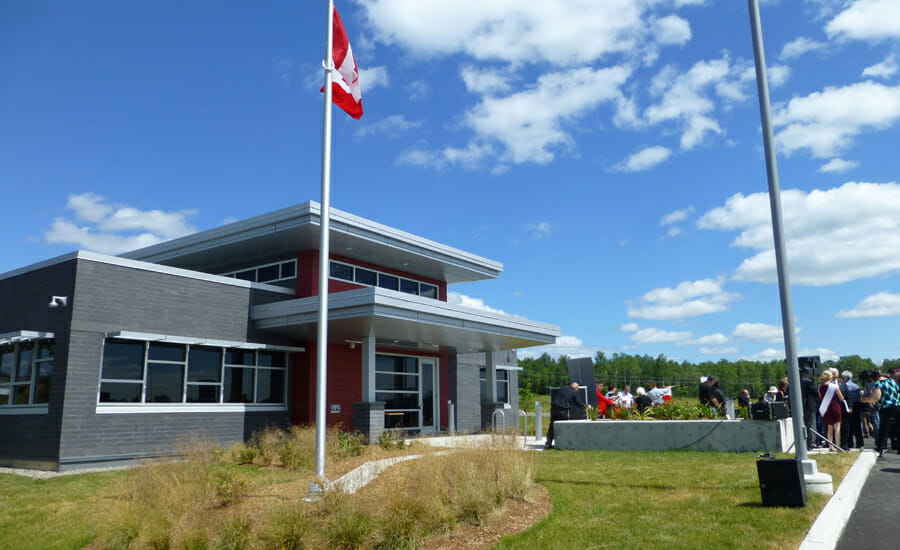 Un groupe de personnes debout devant un bâtiment avec un drapeau canadien.