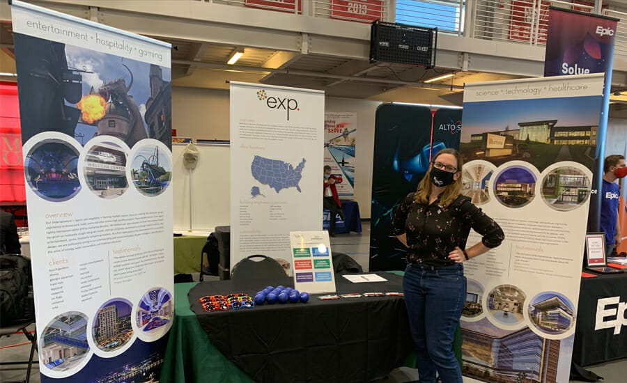 A woman standing in front of a booth at an event.