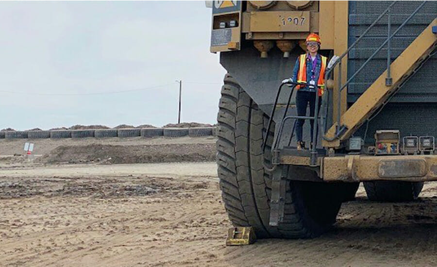 A man standing on the back of a large dump truck.