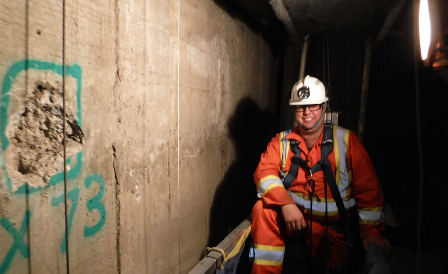 A construction worker in a tunnel with graffiti on the wall.