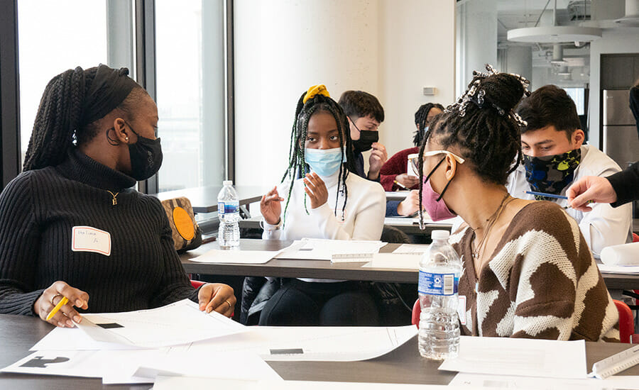 A group of people sitting at a table wearing face masks.