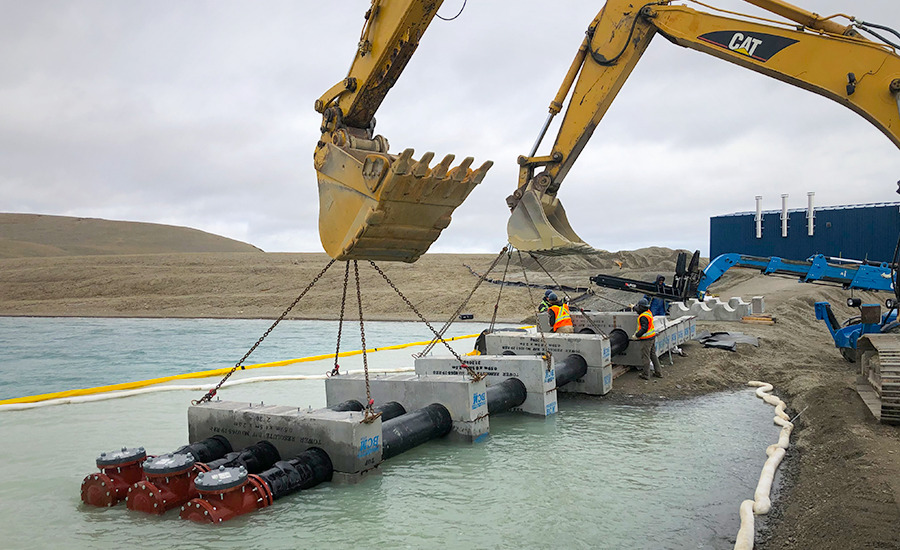 A bulldozer is lifting a pipe into the water.