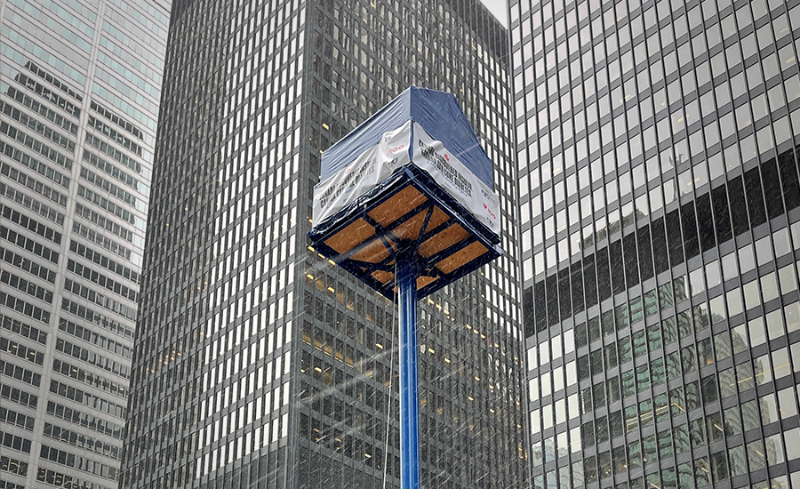 Une boîte bleue posée sur un poteau devant de grands immeubles.