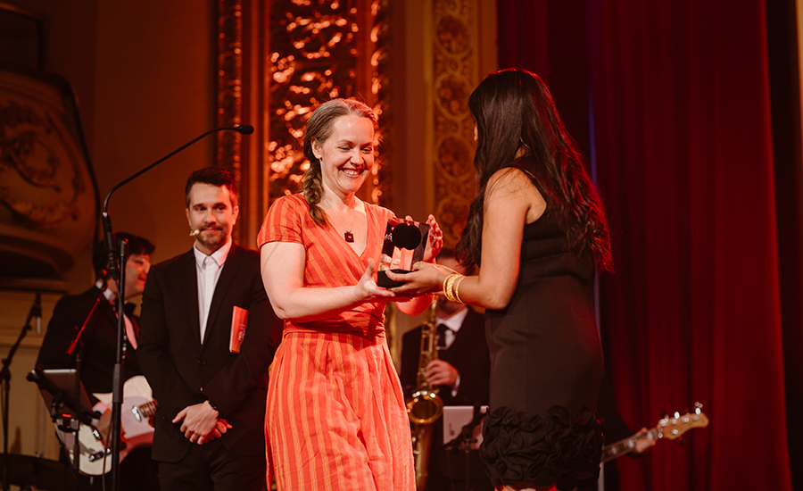 A woman receives an award from a man on stage.