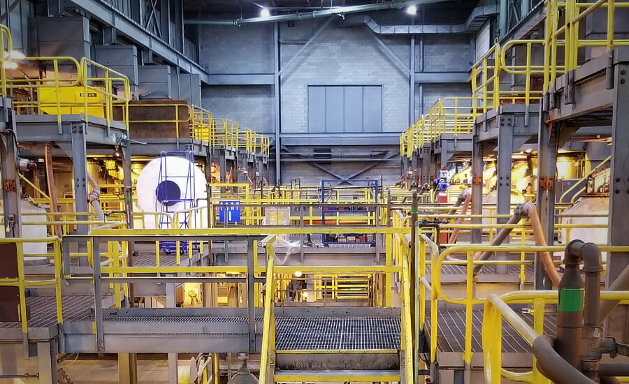 The inside of a large factory with yellow railings.