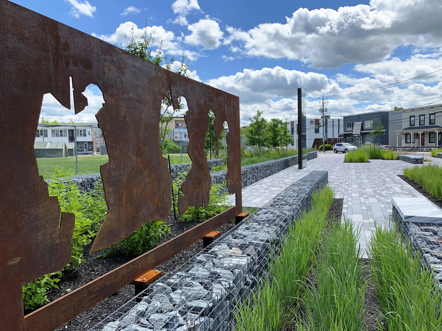 A rusty metal sculpture sits in the middle of a grassy area.