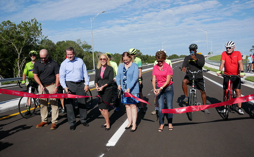A group of people cutting a ribbon on a road.