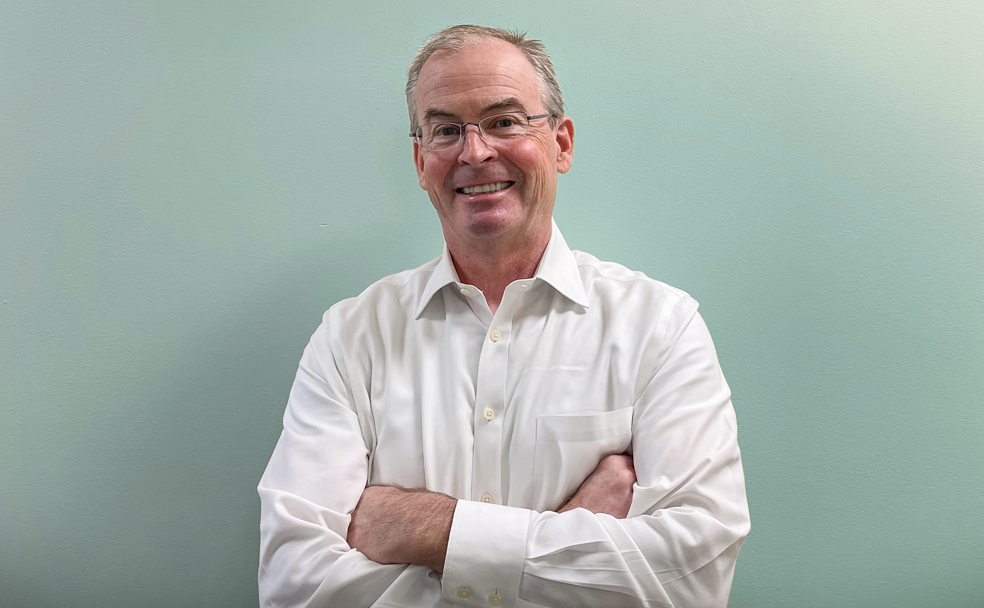 A man in a white shirt with his arms crossed.