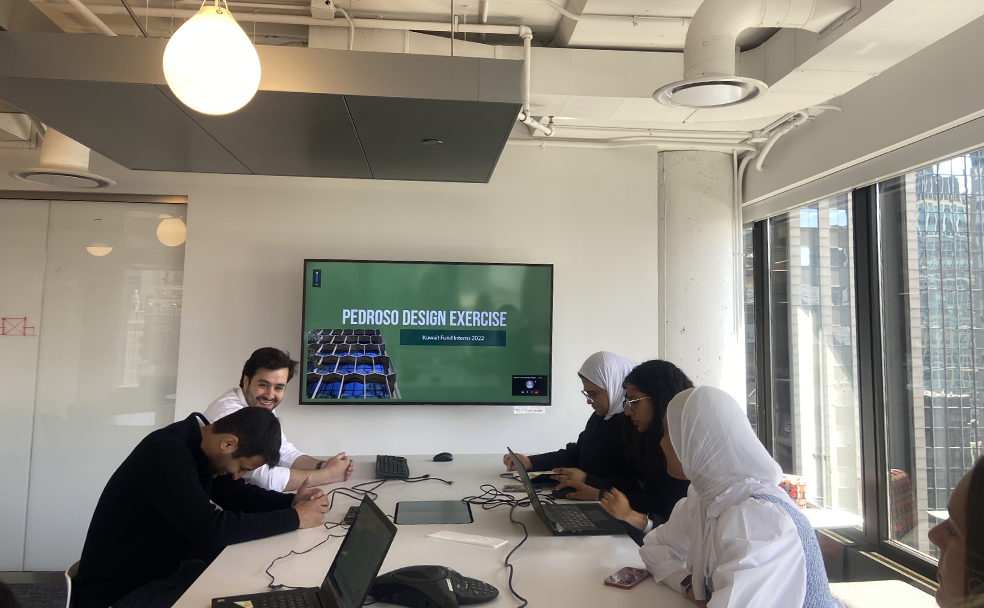 A group of people sitting around a table with laptops.